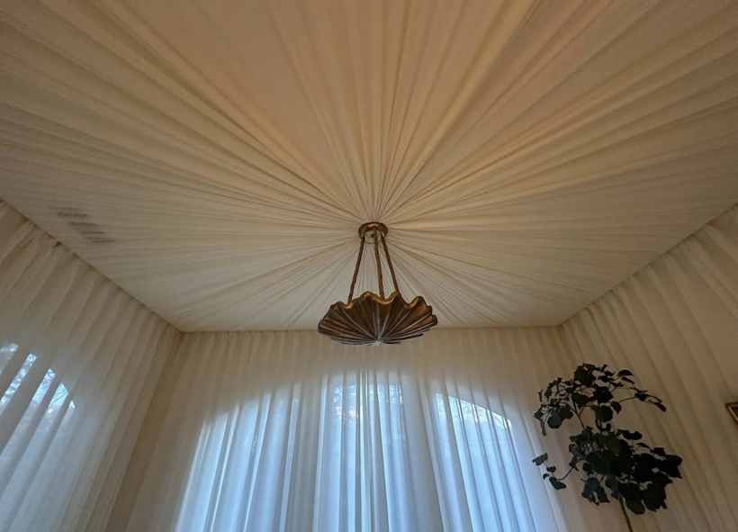 Radial gathered fabric ceiling with a shell chandelier