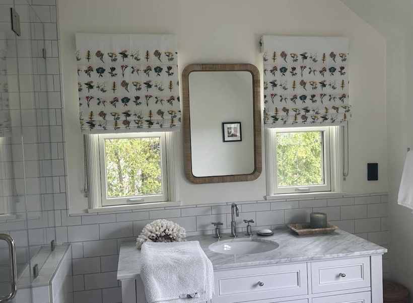 Botanical roman shades over a marble bath vanity